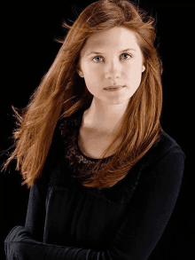 a woman with long red hair and blue eyes is wearing a black shirt