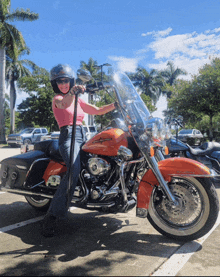 a woman wearing a helmet stands on a harley davidson motorcycle