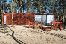 a small house with a wooden deck and stairs