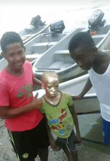 a boy with gold paint on his face is standing next to two other boys in front of boats