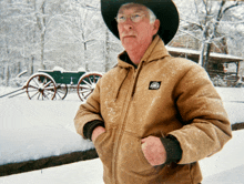 a man wearing a cowboy hat and a brown jacket with the word dickies on the chest