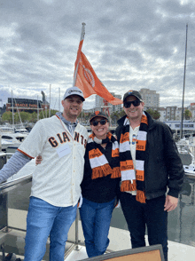 a man wearing a giants jersey is standing with two other people