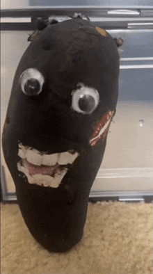 a black object with googly eyes and a smile on it 's face