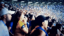 a crowd of people in a stadium with a woman wearing a yellow shirt with the letter t on it