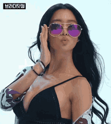 a woman wearing sunglasses and a black bra is blowing a kiss at the camera