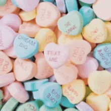 a pile of colorful candy hearts with messages on them .