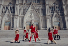 a group of women in red dresses are dancing in front of a building that says ' sydney ' on it