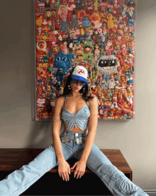 a woman wearing a sesame street hat is sitting in front of a painting