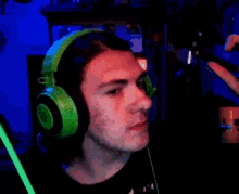 a man wearing green headphones holds his nose