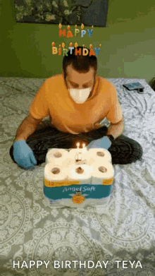 a man wearing a mask and gloves is sitting on a bed with a birthday cake made out of toilet paper