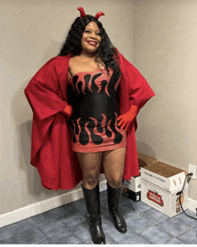 a woman in a devil costume stands in front of a box of stella artois