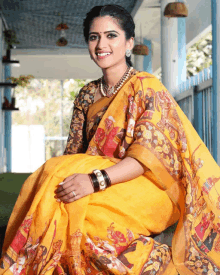 a woman wearing a yellow saree with a painting on it