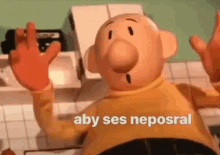 a cartoon character is sitting on a kitchen counter with his hands up and the words aby ses neposral written above him .