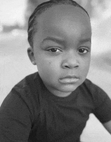 a black and white photo of a little boy looking at the camera