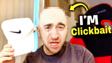 a man is crying while holding a nike hat with the words i 'm clickbait above him