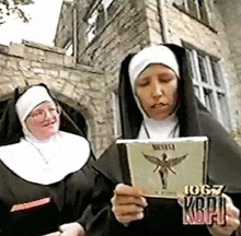 two nuns are standing next to each other and one is holding a cd that says nirvana