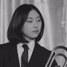 a woman in a suit and tie holds a trumpet
