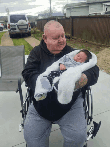 a man in a wheelchair holds a baby in his lap