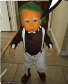 a baby dressed in a costume with green hair and orange face paint