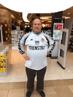 a man wearing a shirt that says stienstra stands in a store