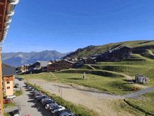 a row of cars are parked on the side of a road in front of a mountain village