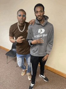 two men are posing for a picture and one has a mossy oak hoodie on