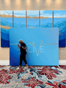 a woman stands in front of a blue sign that says " live "