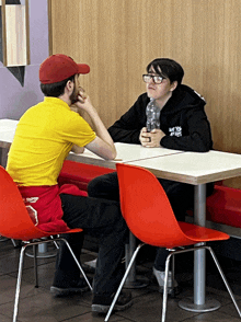 a man in a yellow shirt with the word coca cola on it sits at a table with a woman