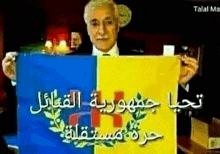 a man in a suit is holding a blue and yellow flag with arabic writing on it