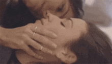 a woman is kissing another woman on the forehead while laying on a bed .