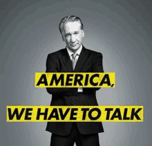 a man in a suit and tie is standing in front of a sign that says " america we have to talk "