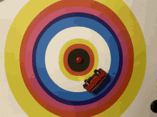 a red toy car is on a colorful target