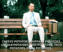 a man in a suit is sitting on a wooden bench with a suitcase and a pizza