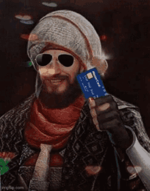 a man wearing sunglasses and a hat holds a mastercard credit card