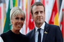 a man and a woman are standing next to each other in front of flags .