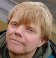 a close up of a man 's face with blonde hair and a beard .