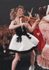 a woman in a white and black dress is playing a violin