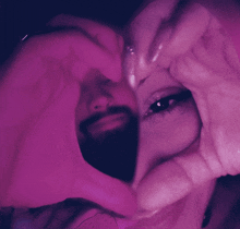 a woman making a heart shape with her hands in front of her face