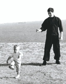 a black and white photo of a man and a child playing in the dirt .