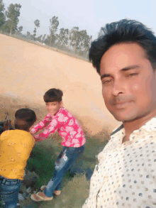 a man in a polka dot shirt poses for a picture with two children in a field