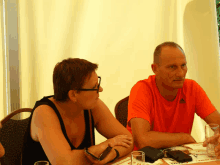 a man in an orange adidas shirt sits at a table