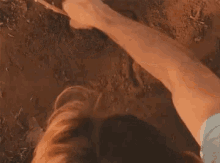 a close up of a person 's hand holding a stick in the dirt