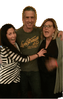 a man wearing a levi strauss t-shirt is hugging two women