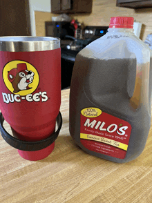 a bottle of milo 's famous sweet tea sits next to a red cup