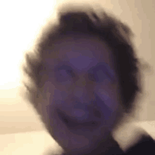 a blurry picture of a person 's face with a purple light behind them .