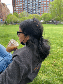 a woman wearing glasses and a face mask drinking a cup of coffee