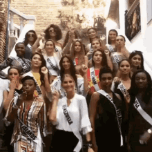 a group of women are standing next to each other on a set of stairs wearing sashes that say miss universe .