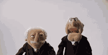 two muppets in suits are standing next to each other .