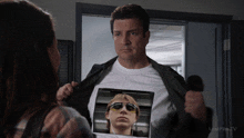 a man is wearing a t-shirt with a picture of a man with sunglasses on his chest