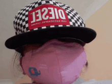 a person wearing a pink face mask and a hat that says diesel